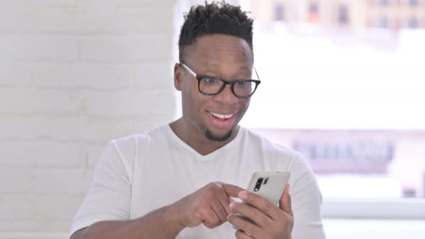 Retrato do homem africano casual comemorando o sucesso no smartphone — Vídeo de Stock