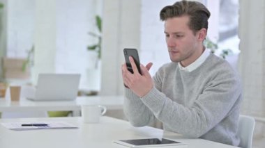 Akıllı telefonda Başarı Kutlaması Yaratıcı Genç Adam 