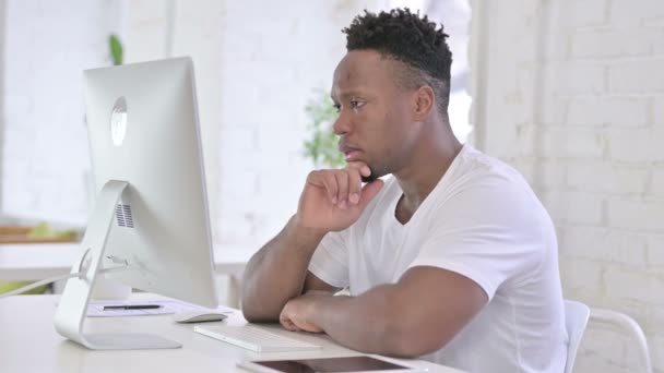 Tillfällig afrikansk man tänker och arbetar på skrivbordet — Stockvideo