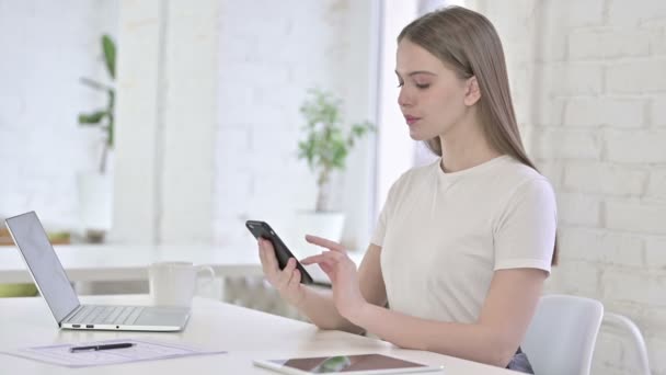 Mujer joven y feliz hablando por teléfono inteligente en la oficina — Vídeo de stock