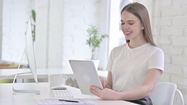 Молодая женщина ведет видео-чат на планшете в офисе — стоковое видео