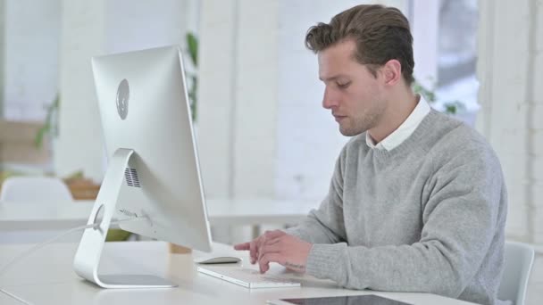 Geschokt creatieve jonge man reageert op mislukking op Desktop — Stockvideo