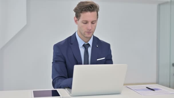 Ofiste dizüstü bilgisayar üzerinde çalışan odaklanmış genç iş adamı — Stok video