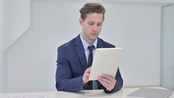 Hardwerkende jonge zakenman met behulp van Tablet in Office — Stockvideo