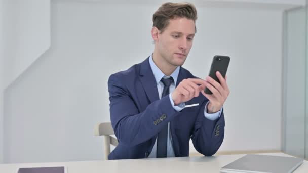 Joven Empresario Alegre usando Smartphone en Office — Vídeos de Stock