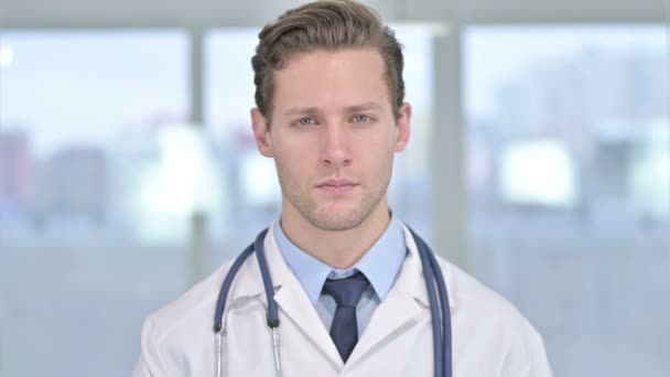 Portrait de jeune homme médecin regardant la caméra au bureau — Video