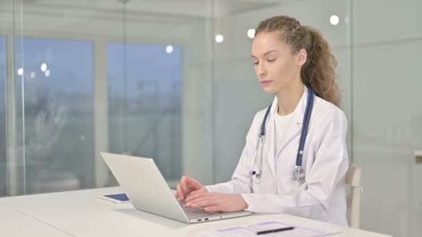 Hermosa joven médico femenino que trabaja en el ordenador portátil y sonriendo — Vídeos de Stock