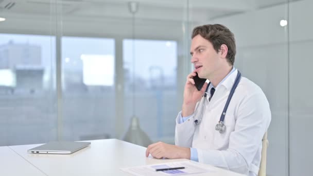 Счастливый молодой врач разговаривает на смартфоне — стоковое видео