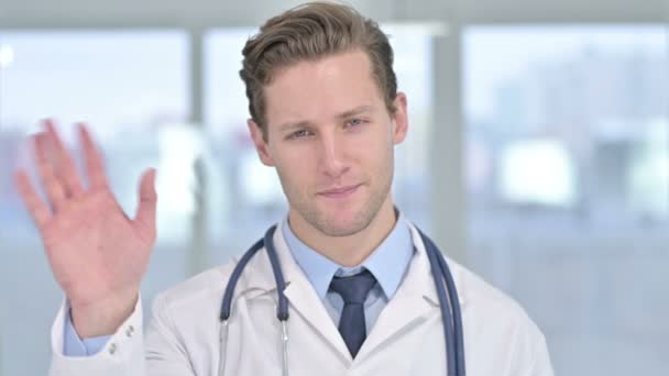 Porträt eines fröhlichen jungen männlichen Arztes beim Videochat im Büro — Stockvideo
