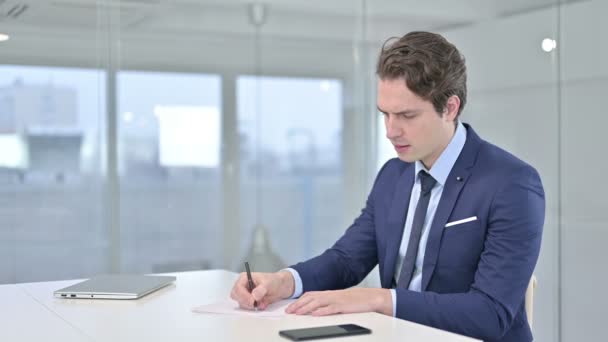 Jonge zakenman denkend en werkend aan papieren — Stockvideo