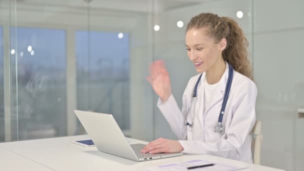 Jovem alegre médico feminino fazendo vídeo chat no laptop — Vídeo de Stock