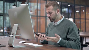 Öfkeli Adam Bilgisayar üzerinde çalışırken Smartphone 'dan çağrı aldı