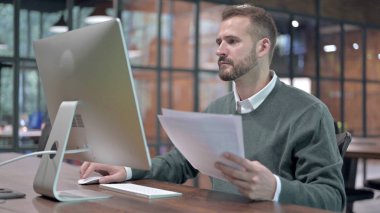 Belge ve Bilgisayar üzerinde çalışan Yakışıklı Adam