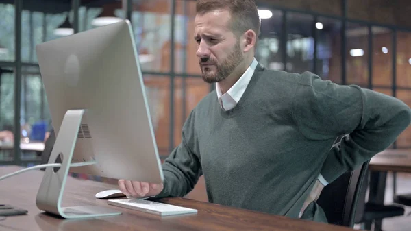 Cansado homem tendo dor nas costas enquanto trabalhava no desktop — Fotografia de Stock