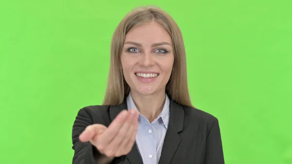 Empresária alegre Convidando pela mão assinar contra Chroma Key — Fotografia de Stock