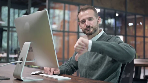 Homem inteligente trabalhando no computador e mostrando polegares para baixo — Fotografia de Stock