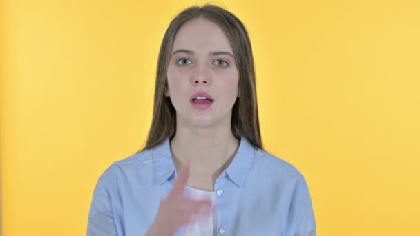 Casual jonge vrouw zetten vinger op lippen, gele achtergrond — Stockvideo