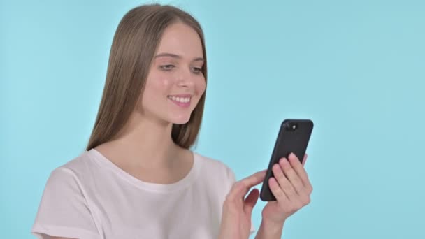 Красивая молодая женщина с помощью смартфона, синий фон — стоковое видео