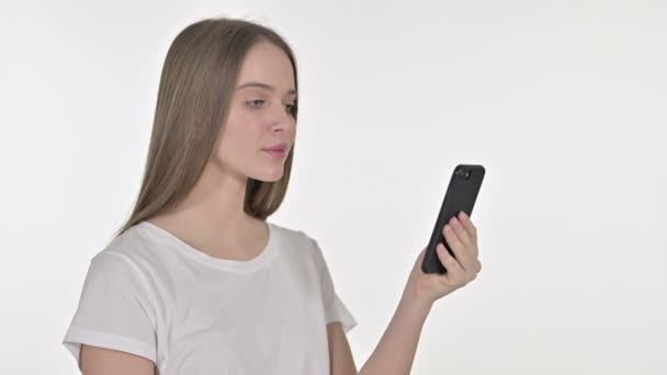 Hermosa mujer joven frente a la pérdida en el teléfono inteligente, fondo blanco — Vídeos de Stock