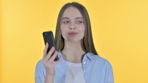 Lässige junge Frau im Gespräch auf Smartphone, gelber Hintergrund — Stockvideo