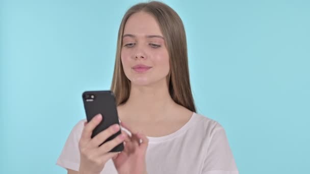 Hermosa mujer joven hablando en Smartphone, fondo azul — Vídeos de Stock