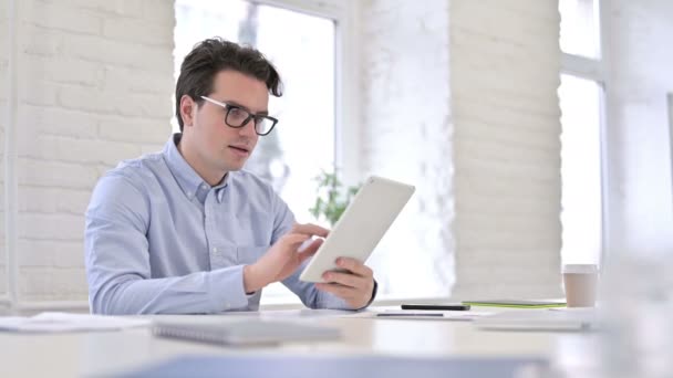 Wesoły młody człowiek pracy za pomocą tabletu w nowoczesnym biurze — Wideo stockowe