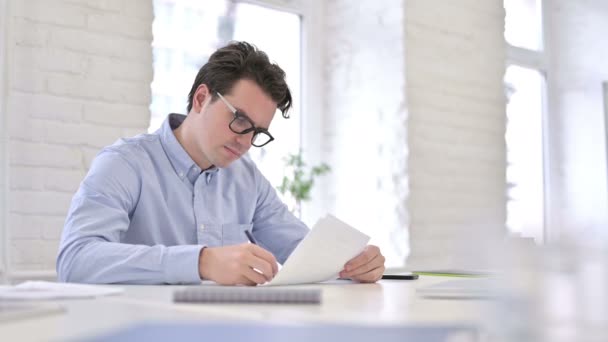 Attractive Working Young Man Reading Documents in Office — ストック動画