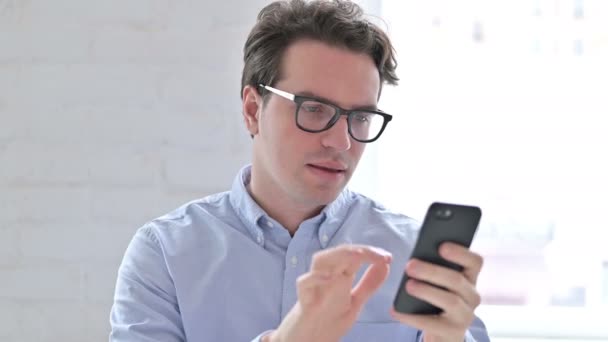 Retrato del joven celebrando el éxito en el teléfono inteligente — Vídeos de Stock