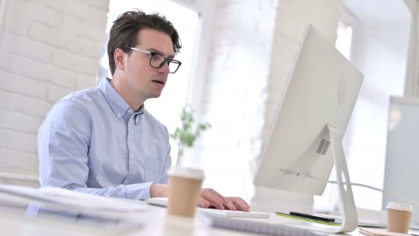 Εστιασμένος εργαζόμενος νεαρός άνδρας πίνοντας καφέ και χρησιμοποιώντας Desktop — Αρχείο Βίντεο