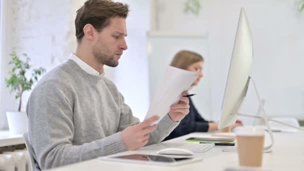 Hombre creativo leyendo documentos y trabajando en el escritorio — Vídeos de Stock