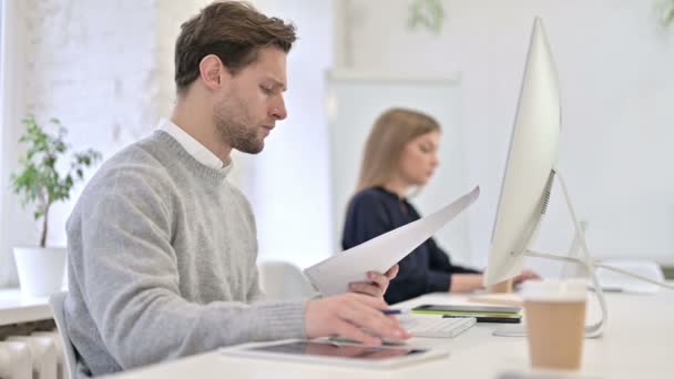 Hombre creativo serio leyendo documentos y utilizando el escritorio — Vídeos de Stock