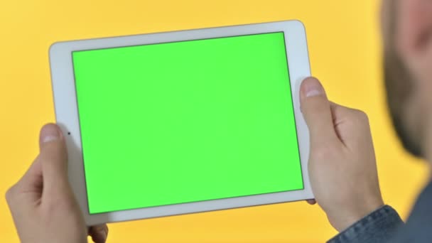 Mann hält Tablet mit Chroma-Bildschirm, gelber Hintergrund — Stockvideo