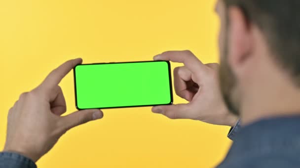 Homem segurando Smartphone com tela Chroma, fundo amarelo — Vídeo de Stock