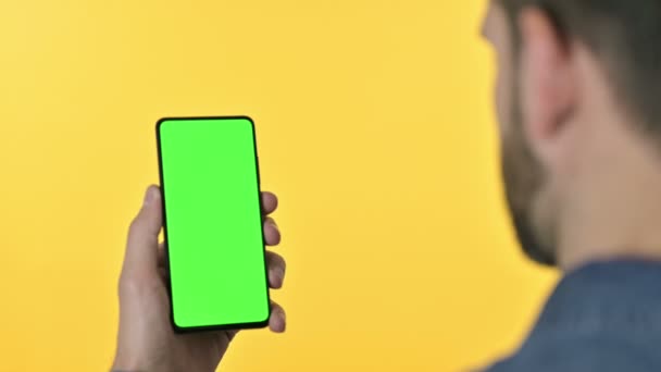 Mann benutzt Smartphone mit Chroma-Bildschirm, gelber Hintergrund — Stockvideo