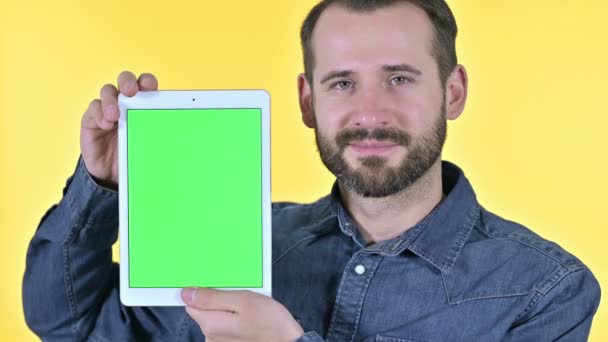 Designer masculino mostrando tela de tablet com tela Chroma, fundo amarelo — Vídeo de Stock