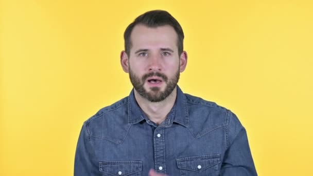 Junger Mann mit Bart feiert mit beiden Fäusten, gelbem Hintergrund — Stockvideo