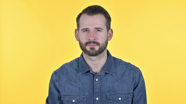 Barba joven señalando con el dedo a la cámara, fondo amarillo — Vídeos de Stock