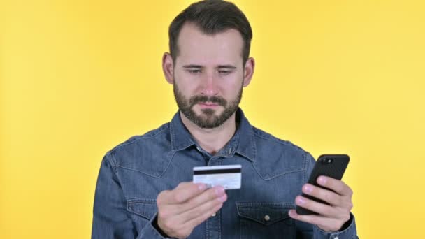 Barba joven haciendo el pago en línea en Smartphone, fondo amarillo — Vídeo de stock