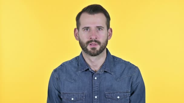 Enttäuschter Bart junger Mann schockiert, gelber Hintergrund — Stockvideo