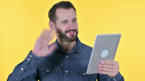 ビデオチャットをタブレットで行うひげの若い男,黄色の背景 — ストック動画