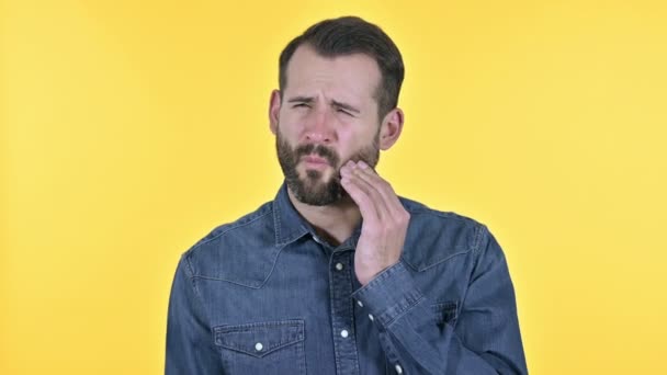 Homem jovem barba com dor de dente, fundo amarelo — Vídeo de Stock