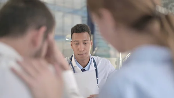 Le couple bouleversé assis devant un jeune médecin africain — Photo