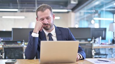 Uykucu genç iş adamı ofis masasında kestiriyor.