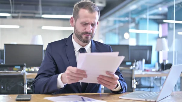 Le jeune homme d'affaires bouleversé lisant les documents au bureau — Photo