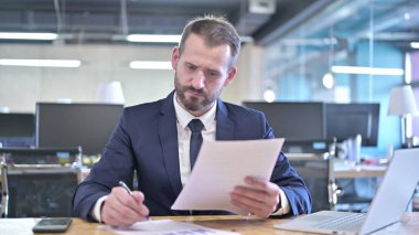 Yakışıklı İşadamı okuma ve belge hazırlıyor.