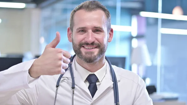 Das Porträt eines fröhlichen jungen Arztes, der die Daumen nach oben zeigt — Stockfoto