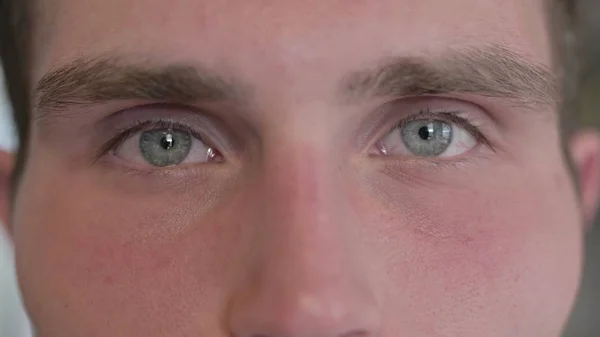 De close-up van de jonge man knipperende ogen in de camera — Stockfoto