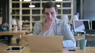 Şaşırmış Genç Tasarımcı Ofiste Dizüstü bilgisayarda şok geçiriyor.