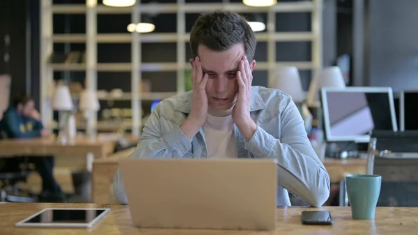 Ciężko pracujący młody projektant z bólem głowy w biurze — Zdjęcie stockowe