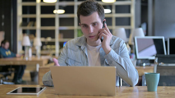 The Attractive Young Designer talking on Smartphone in Office